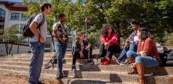 students sitting on steps in front of college hall.