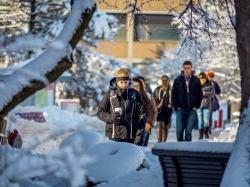 Students bundled up and walking along campus path blanketed by snow.